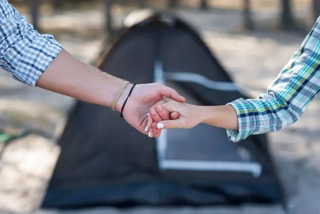 couple holding hands blurred tent